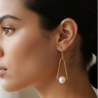 Woman wearing gold drop pearl earrings, minimalist design