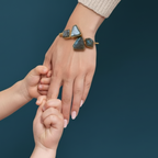 A mother's hand adorned with green raw stone adjustable gold bracelet everyday elegance.