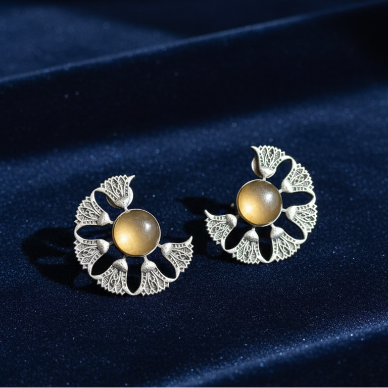 Close-up of statement oxidized stone earrings showcasing intricate stone setting and antique finish on a blue velvet background.