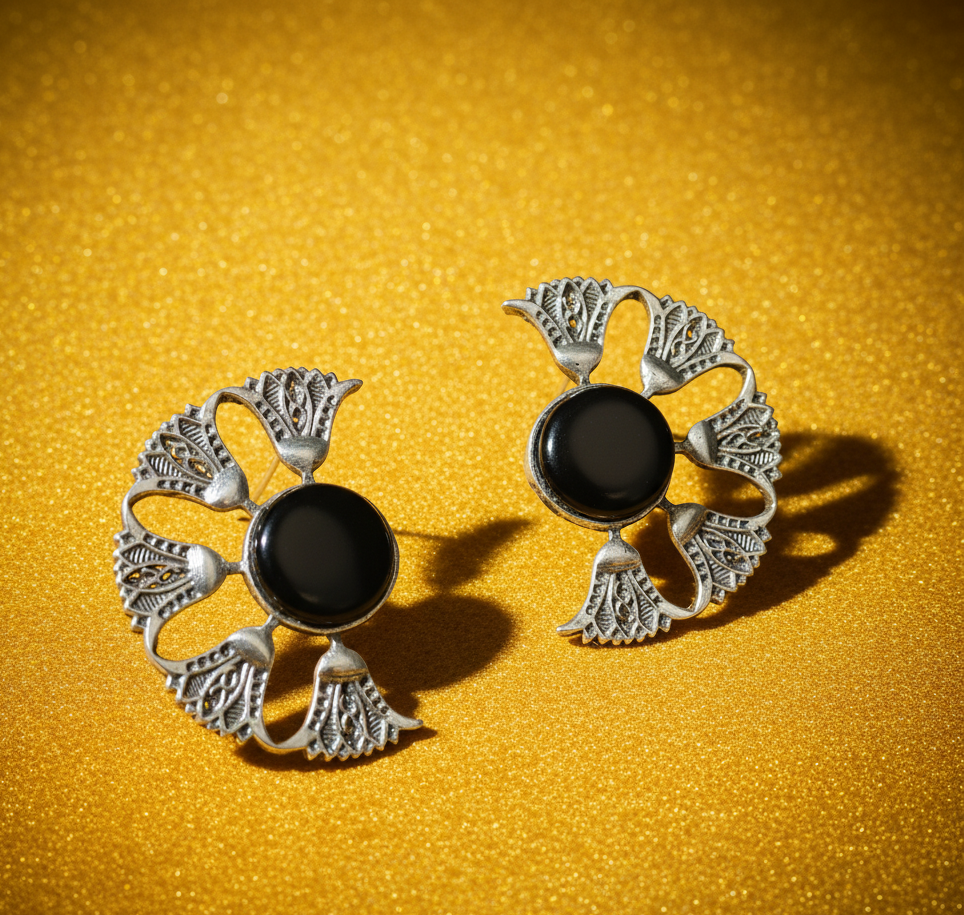Pair of silver earrings withshowcasing intricate stone setting and antique finish on a textured yellow background
