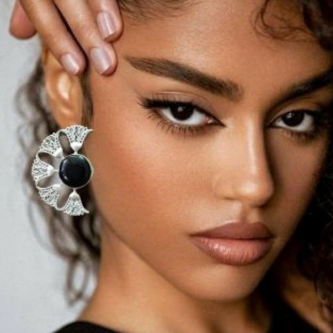 Close-up of a woman wearing a decorative earring with a black center and silver design.