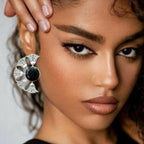 Close-up of a woman wearing a decorative earring with a black center and silver design.