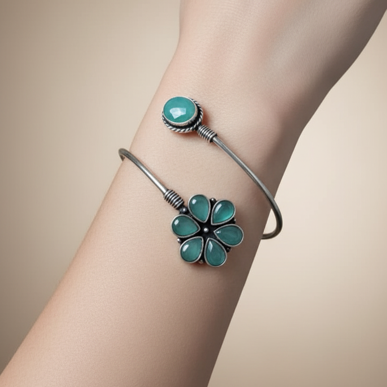 Bracelet with turquoise flower charm on a wrist against a beige background