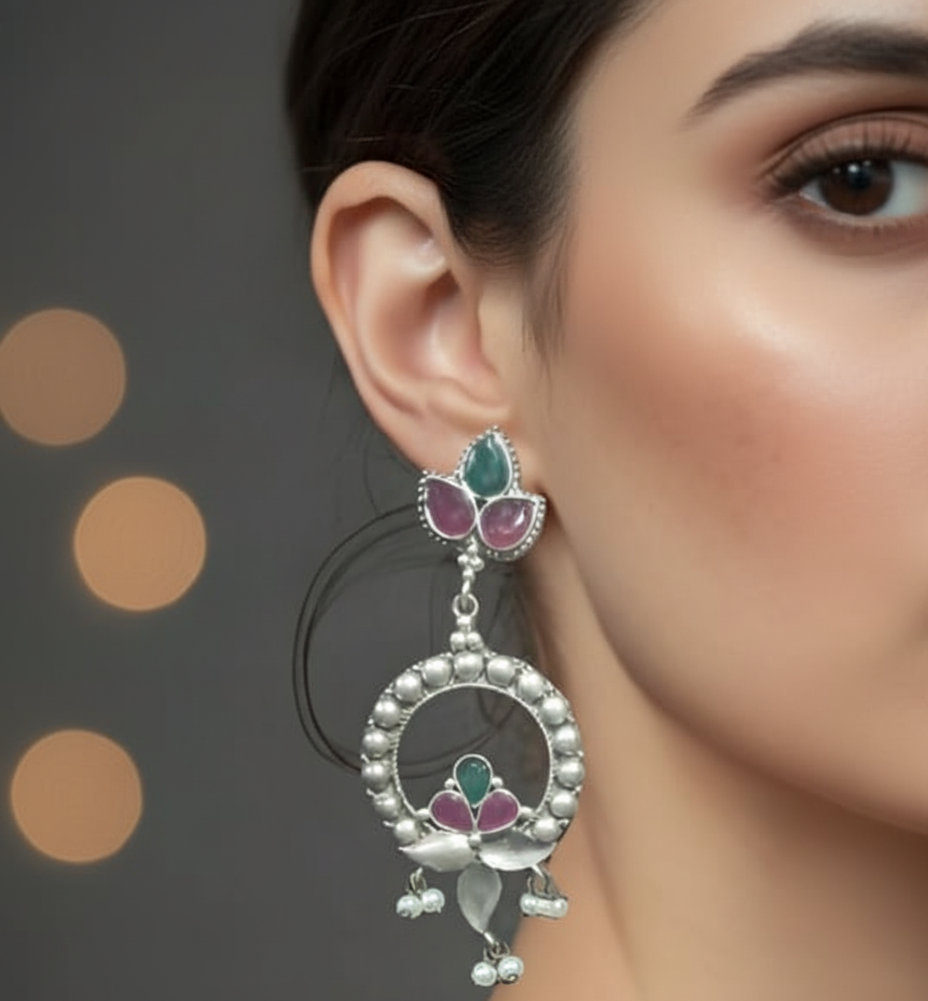 Close-up of a woman wearing a drop & dangle ornate silver earring with gemstones 