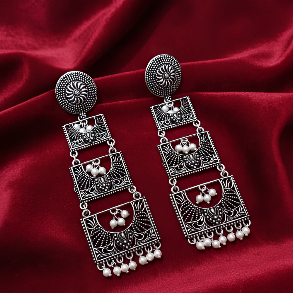 Handcrafted oxidised earrings with a long, layered design on a glossy background