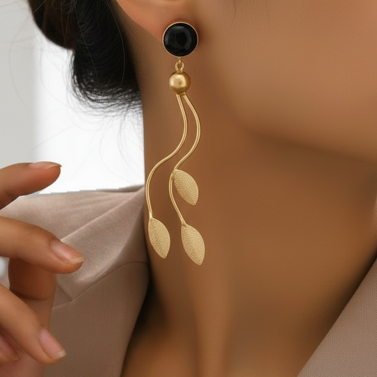 Close-up of a person wearing Long cascading geometric gold plated earrings .