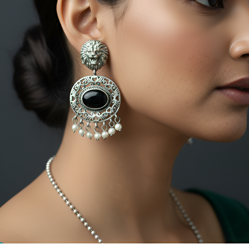Close-up of a woman wearing an ornate silver earring with a black gemstone and pearl accents.