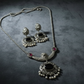 Oxidised silver necklace and earrings set on a dark textured surface