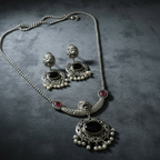 Oxidised silver necklace and earrings set on a dark textured surface