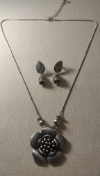 Silver necklace and earrings on a gray background