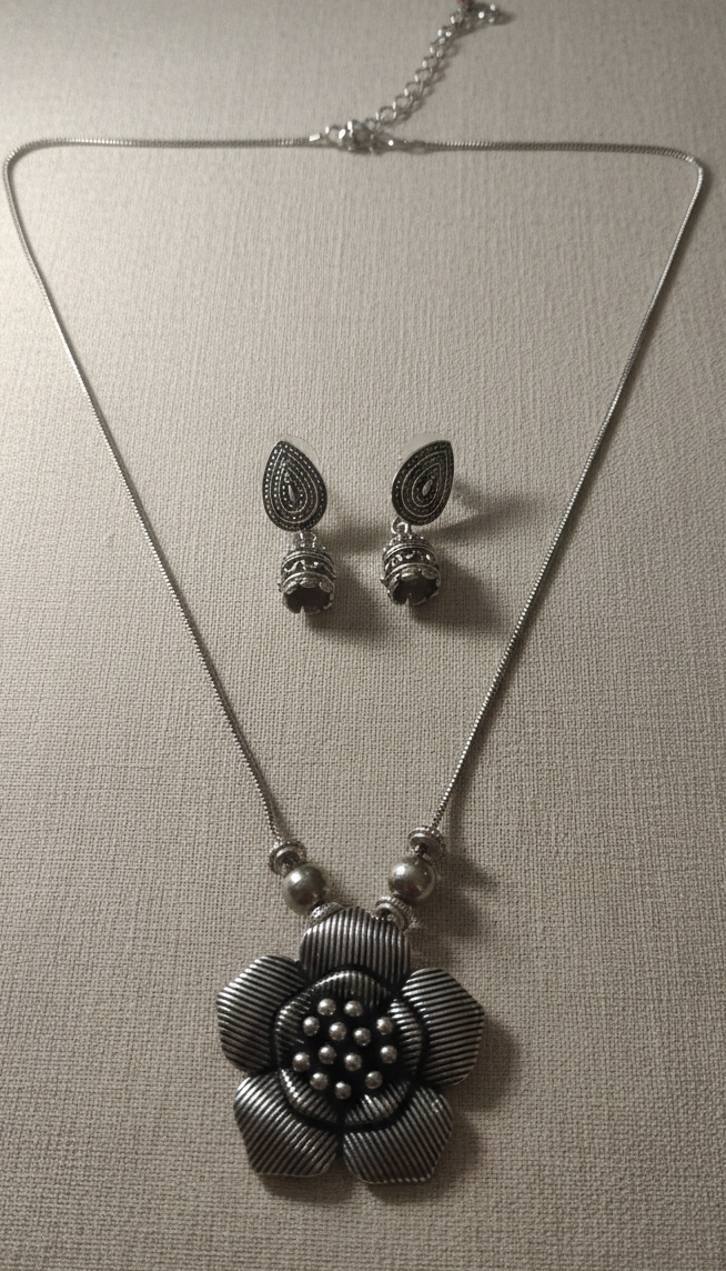 Silver necklace and earrings on a gray background