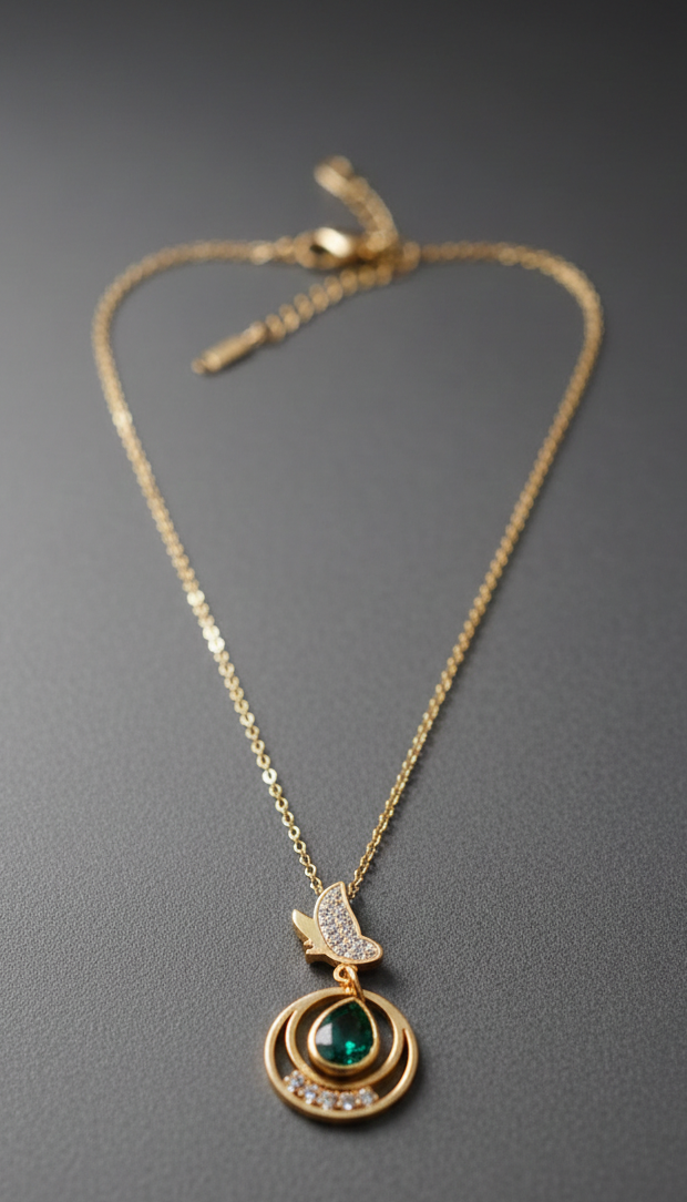 Gold necklace with a pendant featuring a green gemstone & butterfly motifon a gray background