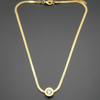 Gold necklace with a diamond stud on a dark gray background