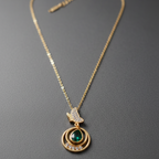 Gold necklace with a green gemstone pendant on a gray background