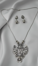 Silver Durga necklace and earrings on a gray fabric background