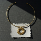 Gold delicate hasli with a pendant on a dark surface