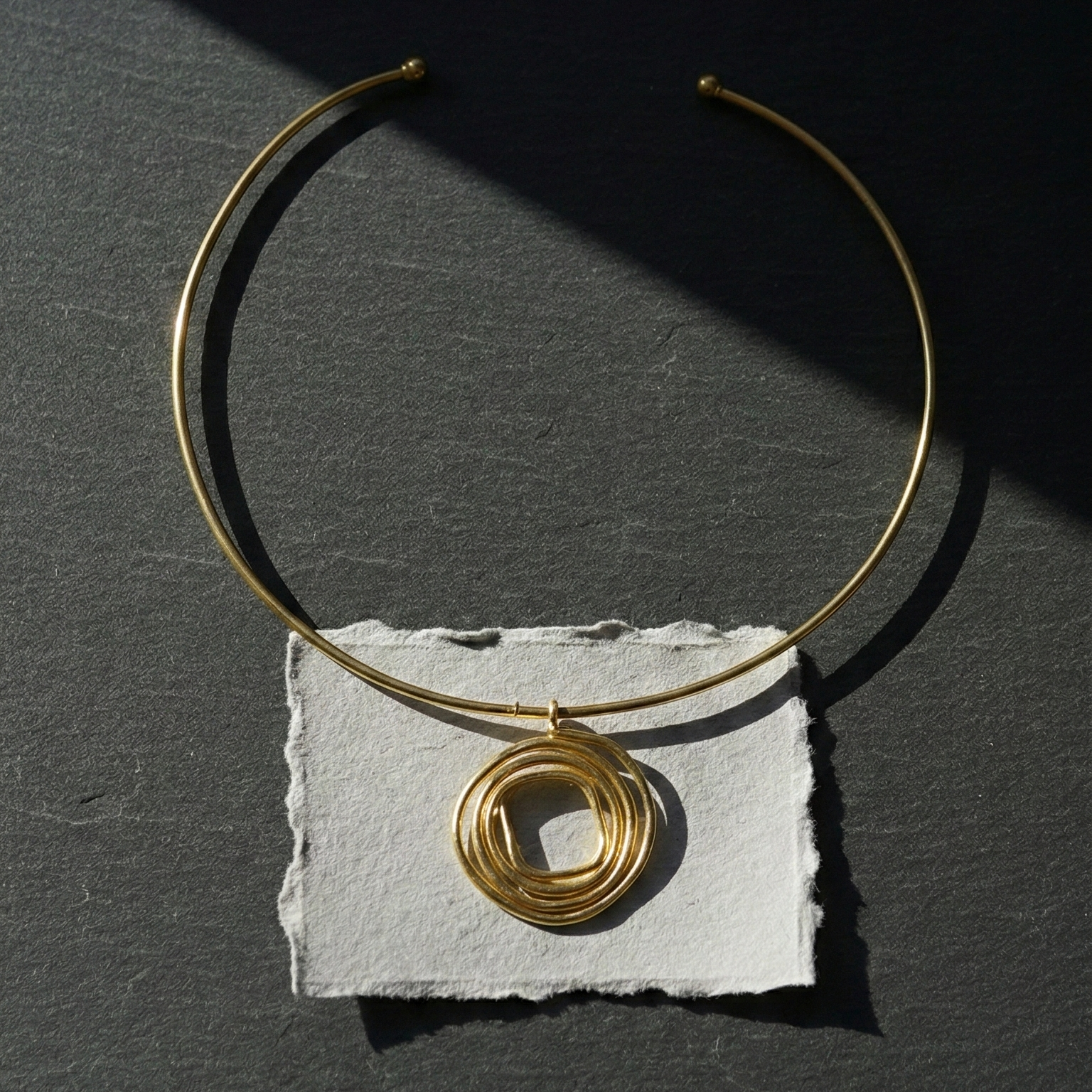 Gold delicate hasli with a pendant on a dark surface