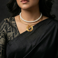 Woman wearing a black saree with minimalist jewelry stack featuring delicate gold hasli & a pearl necklace ideal for office wear.
