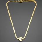 Gold necklace with a diamond stud on a dark gray background