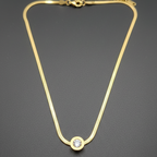 Gold necklace with a diamond stud on a dark gray background