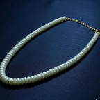 Pearl necklace with gold chain on a dark blue background
