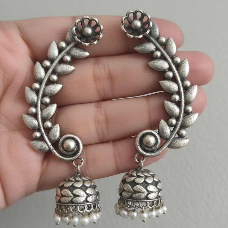 Oxidized silver jhumki earcuffs with intricate detailing in a hand