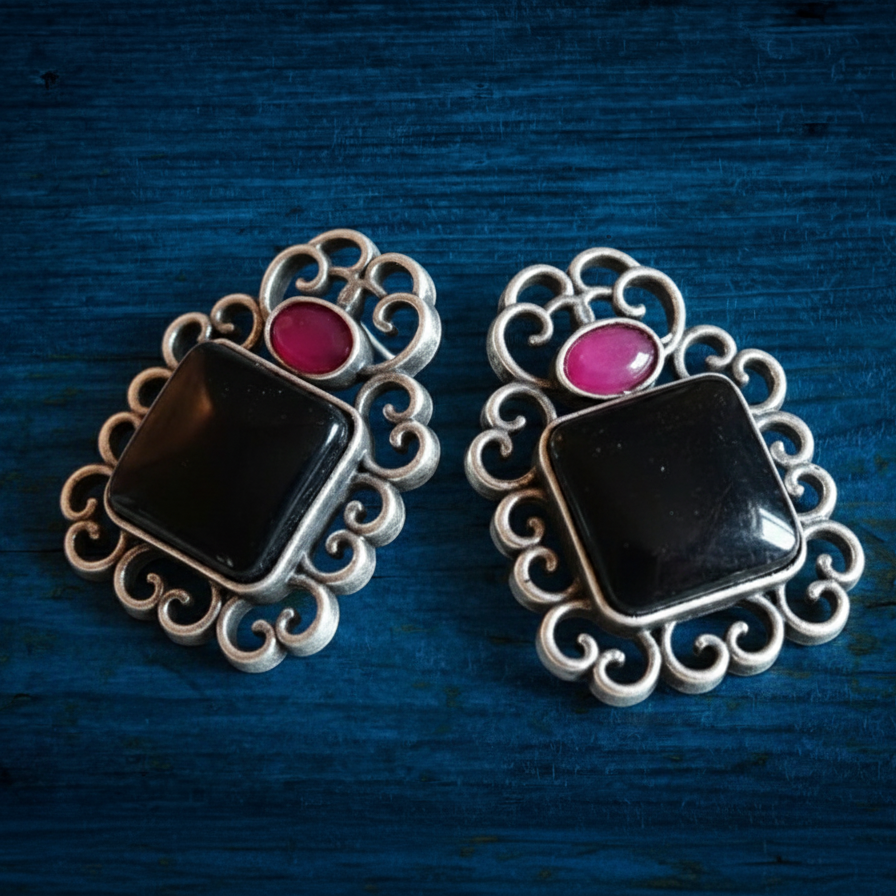 Black & Pink Oxidised stone stud earrings on a Blue Wooden Background.