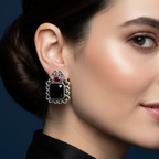 Close-up of a woman wearing a Black & Pink Oxidised stone stud earrings on a textured background, close-up.