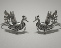 Pair of silver peacock-shaped earcuffs on a light gray background