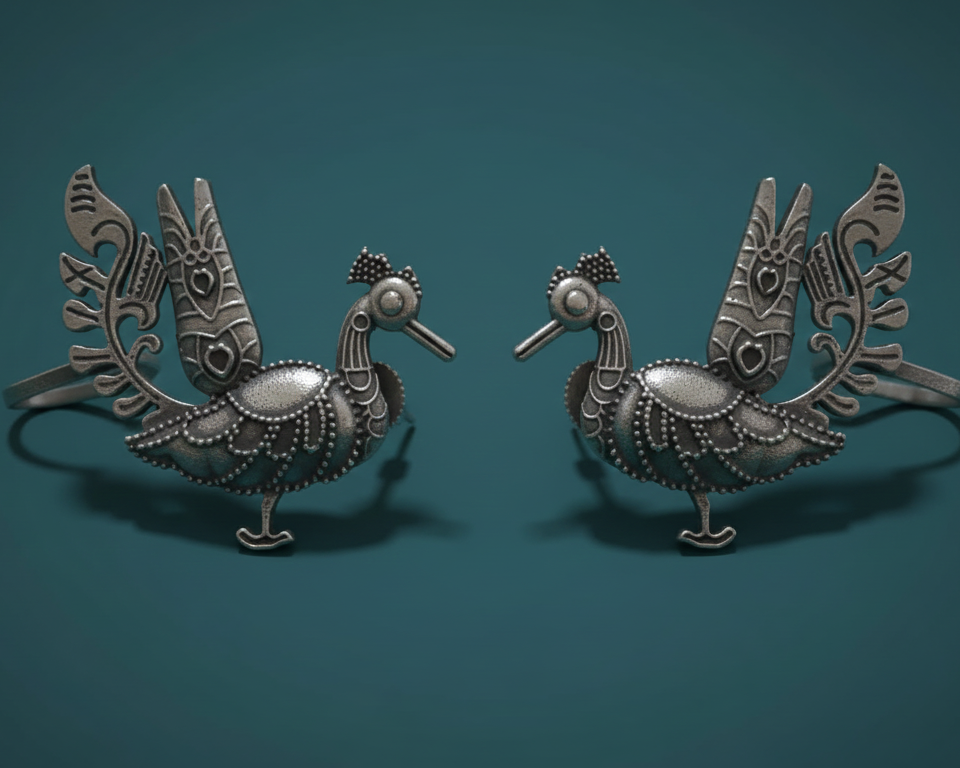 Pair of ornate silver peacock-shaped earcuff on a teal background
