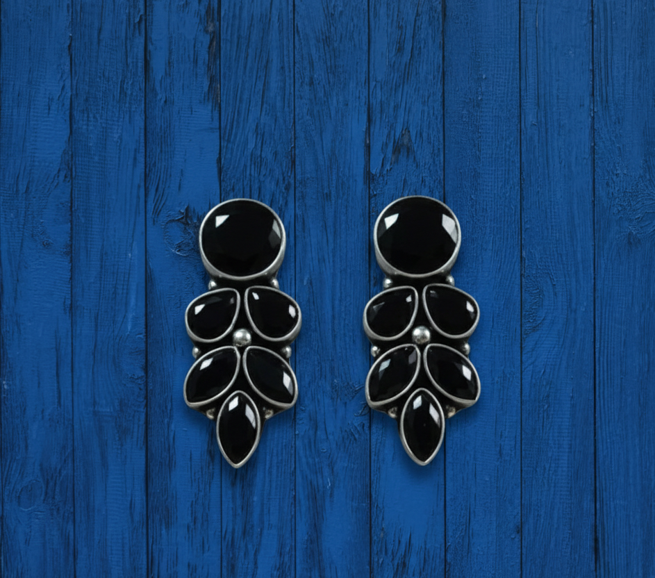 Close-up of [SOOMA] oxidised stone earrings on a blue wooden surface