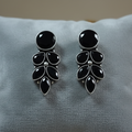 Black and silver earrings on a gray cushion