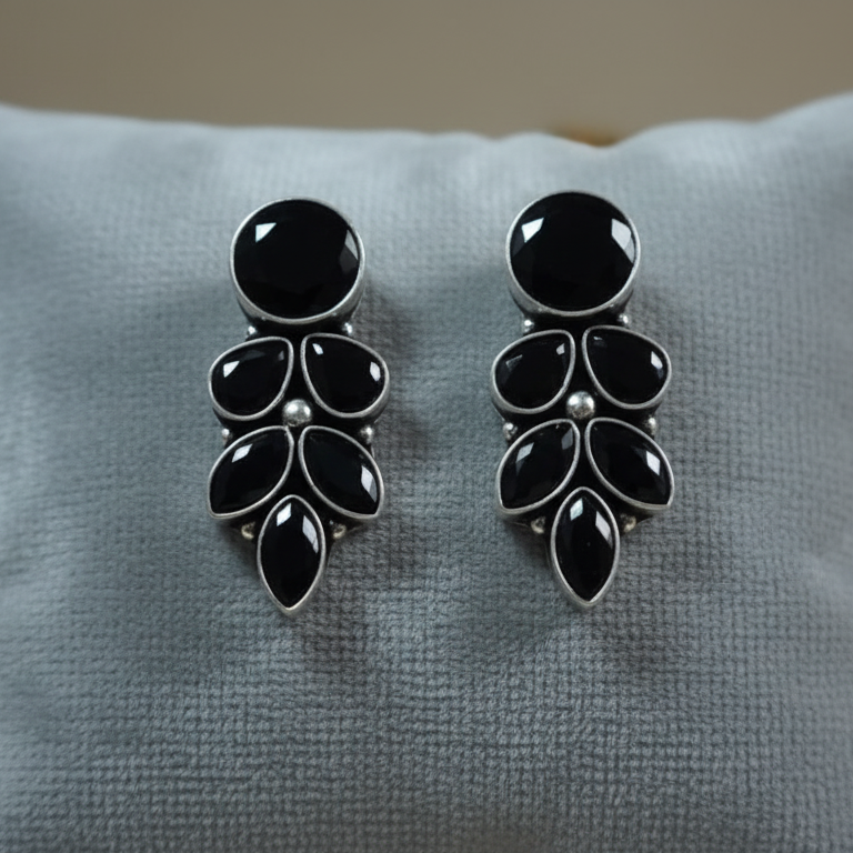 Black and silver earrings on a gray cushion
