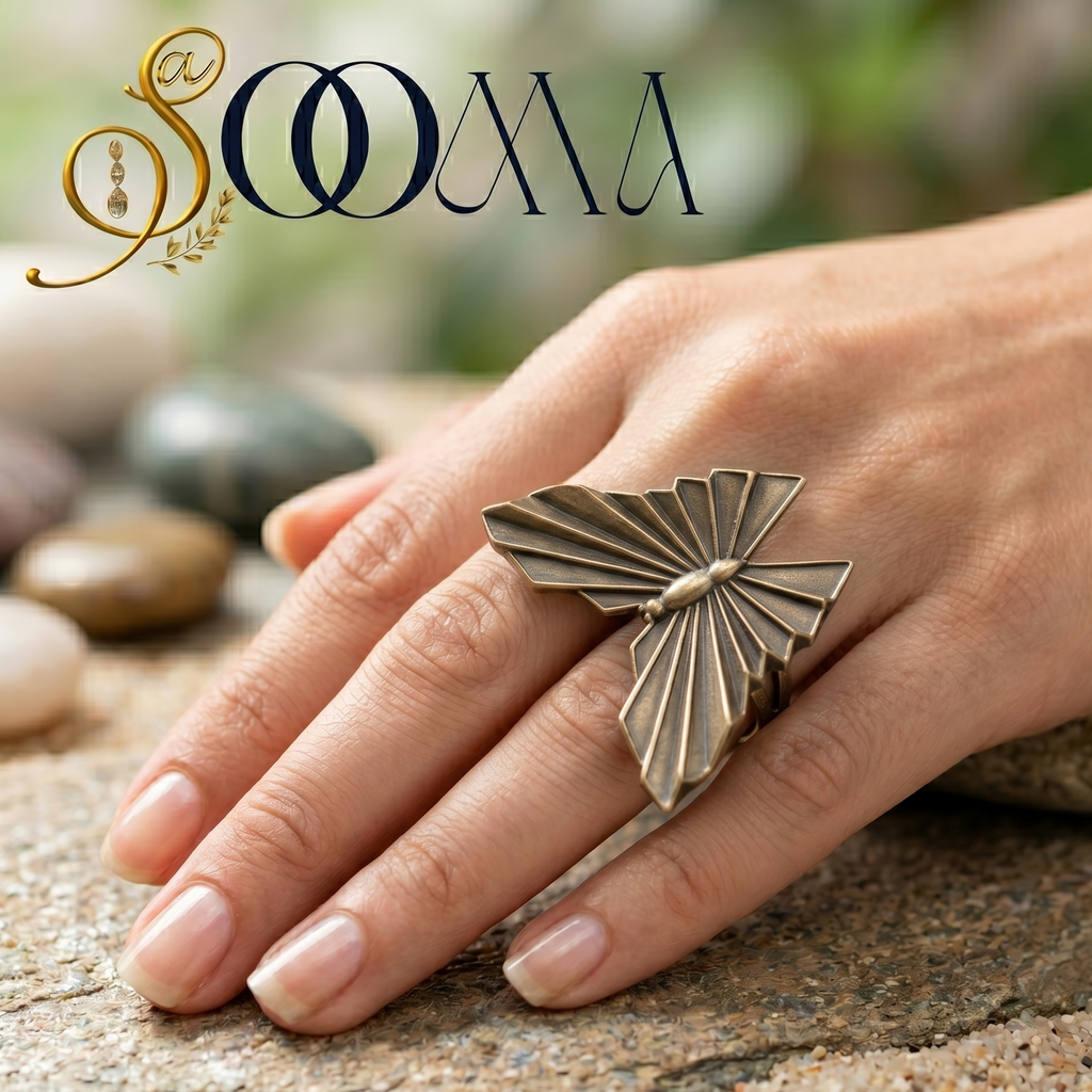 Hand wearing a butterfly-shaped ring on a natural stone surface with 'Sooma' branding.