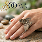 Hand wearing a butterfly-shaped ring on a natural stone surface with 'Sooma' branding.