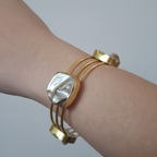 A woman's hand wearing uncut stone gold cuff bracelet imitation with raw finish 