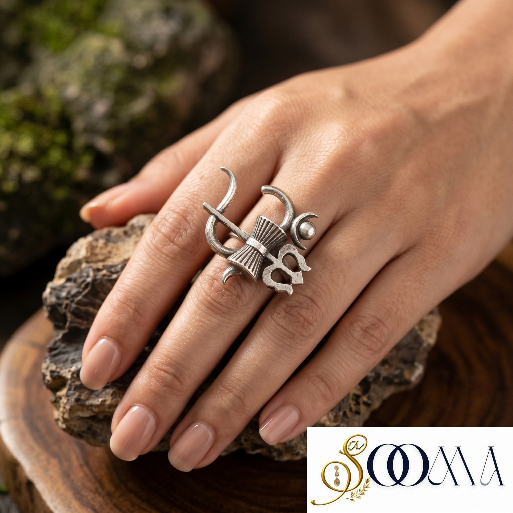 Silver ring with intricate design on a hand, brand logo visible