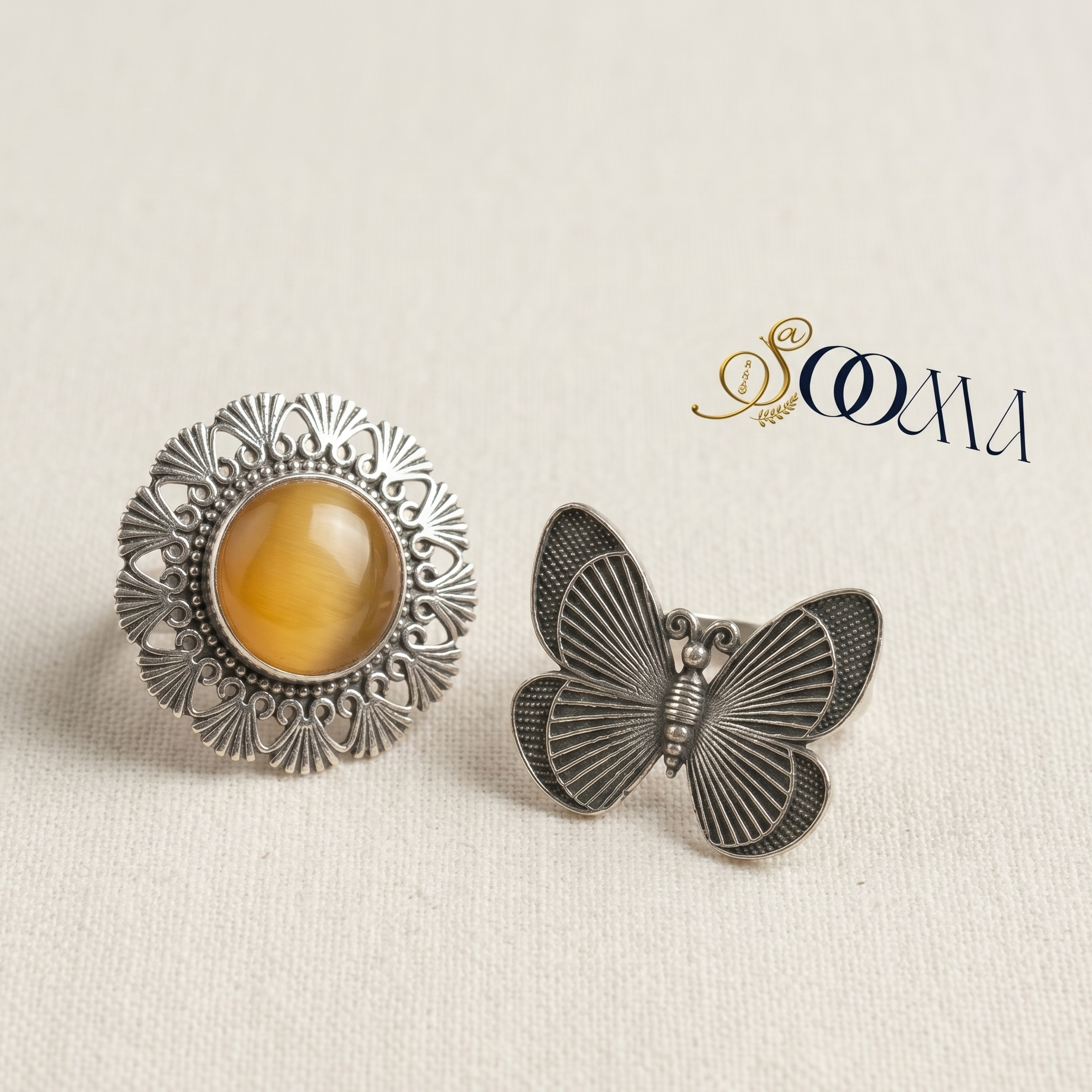 Two earrings, one round with amber stone and the other butterfly-shaped, on a beige background with 'Sooma' branding.