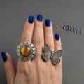 Hand wearing two rings with a gray background, featuring the brand 'Sooma'.