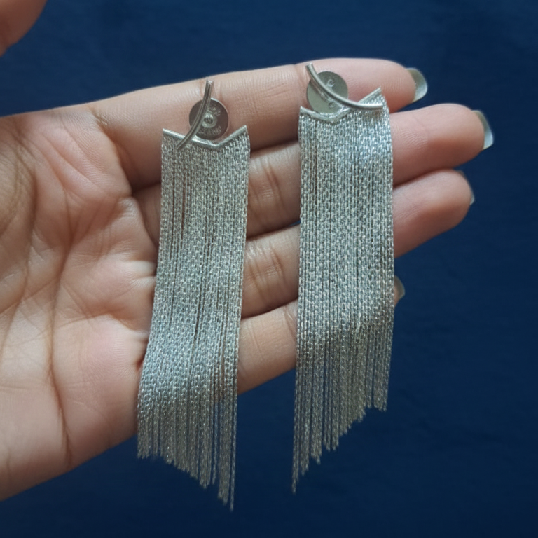 Silver statement earrings with [briefly describe design, e.g., geometric pattern] on a blue background