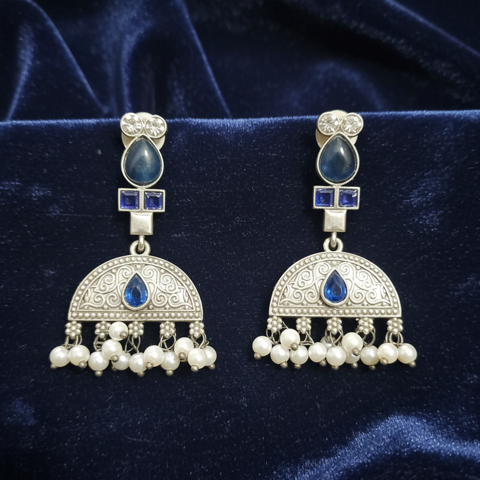 Close-up of Blue Kundan drop earrings showcasing intricate stone settings. on a blue fabric background