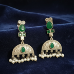 Close-up of Green Kundan drop earrings showcasing intricate stone settings. on a blue fabric background