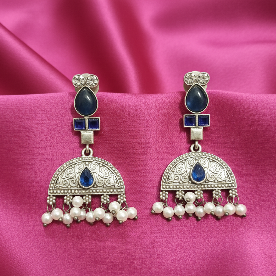 Close-up of Blue Kundan drop earrings showcasing intricate stone settings. on a pink fabric background