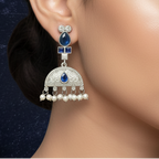 Close-up of a woman wearing Blue Kundan drop earrings showcasing intricate stone settings. on a blue fabric background