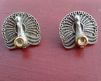 Oxidised silver peacock stud earrings on a colored surface