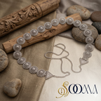 Silver waistbelt  on a wooden stick with stones in the background, featuring the brand 'Sooma'.