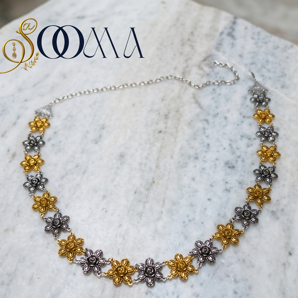Waistband with floral designs in gold and silver on a marble surface, featuring the brand 'Sooma'.