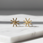 Close-up of Star Gold Earrings showcasing the delicate star design and radiant gold finish on a marble surface.