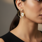 Close-up of a person wearing round stone gold earrings