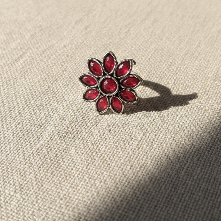 Floral ring with red gemstones on a textured beige surface